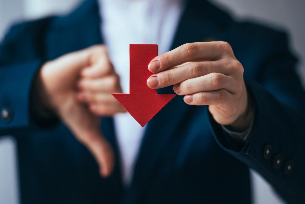 Businessman holding a red arrow pointing downwards symbolizing bankrupcy