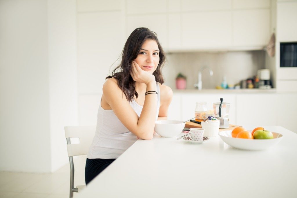 Young smiling woman eating cereal and smiling