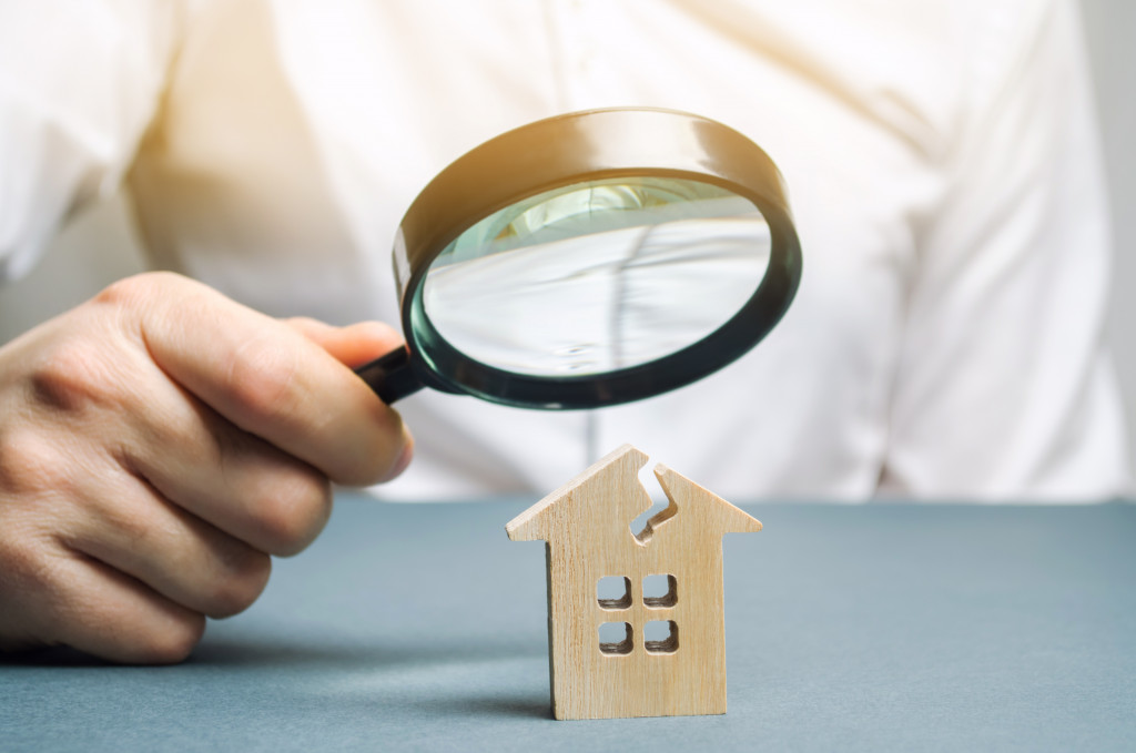 magnifying glass on top of a miniature brown house block