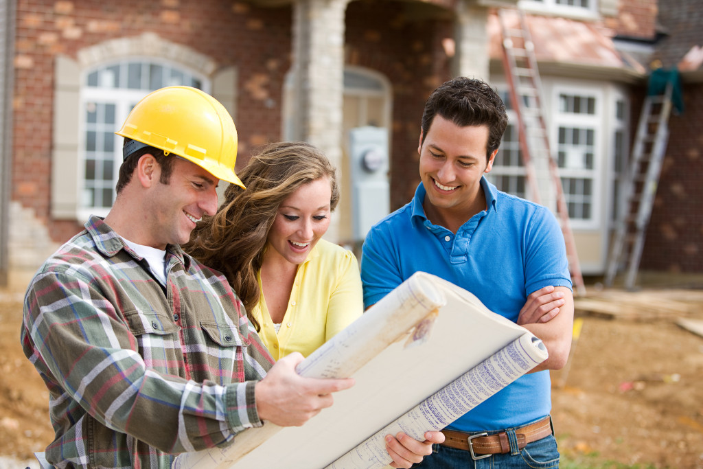A young, happy couple looking at home plans with a builder