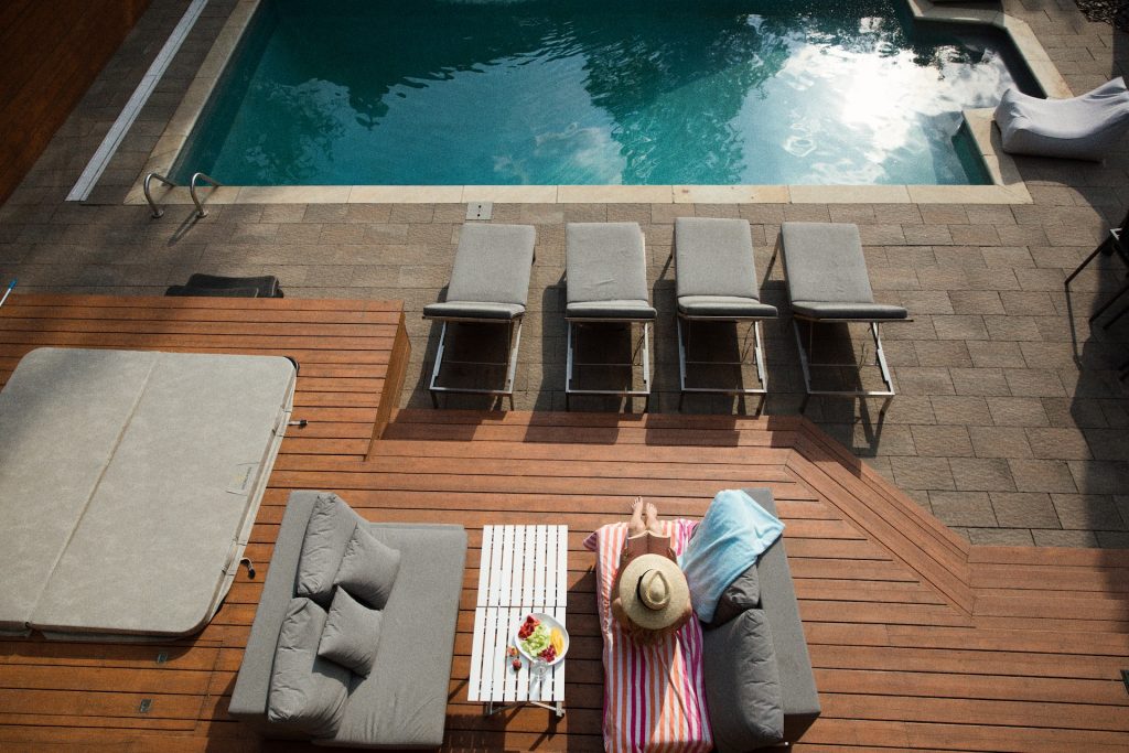 woman in hat reading a book on wooden pool deck
