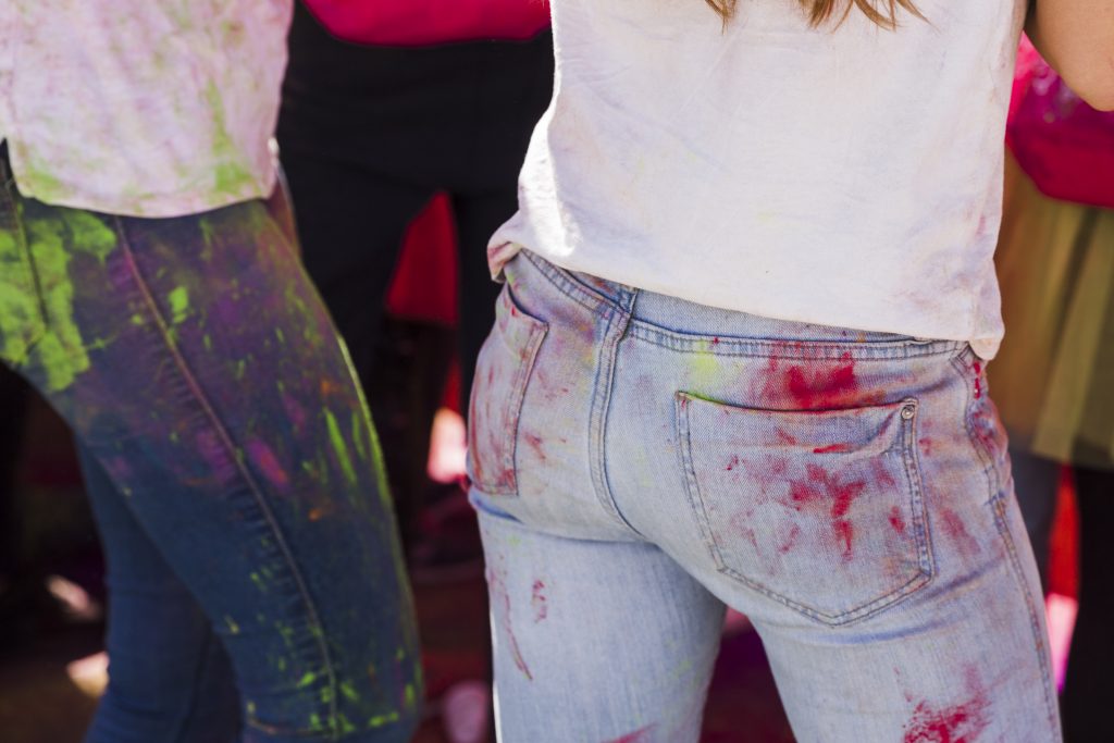two women wearing jeans with paint stains
