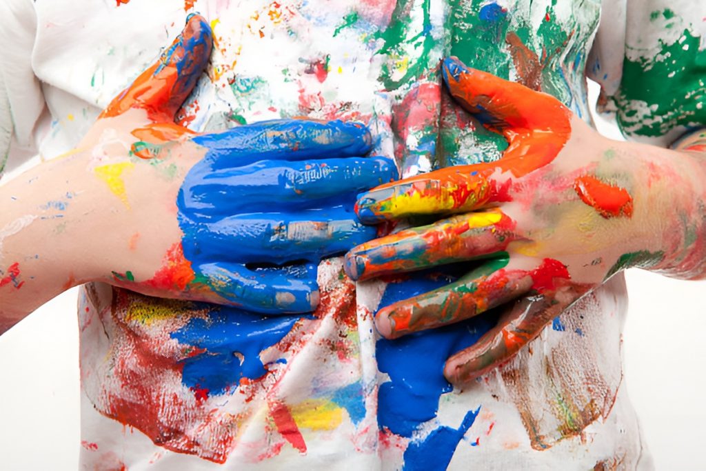 boys with hands covered in paint, touching his white shirt