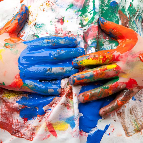 boys with hands covered in paint, touching his white shirt